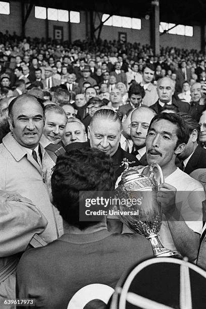 Marseille's captain Jean Djorkaeff holds his team's trophy next to Alain Poher , acting President of the French Republic following the final of the...