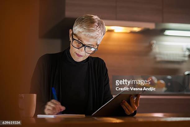 mature woman using computer - busy kitchen stock pictures, royalty-free photos & images