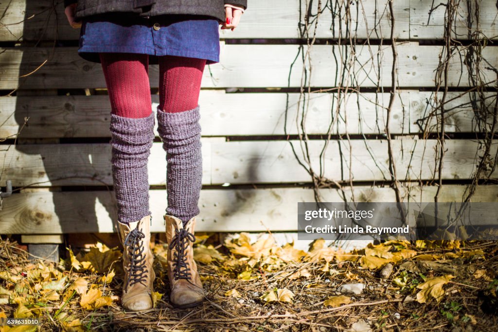 Lower body of a girl who has style that wears boots, red tights and knee socks