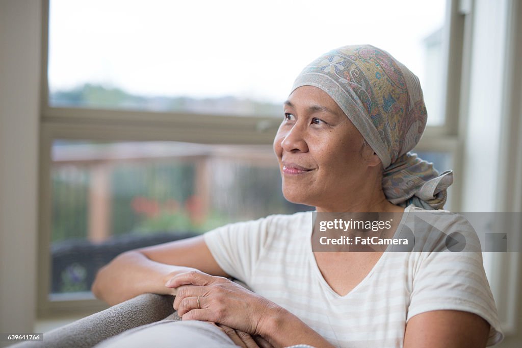 Ethnic female with cancer smiling and looking out the window