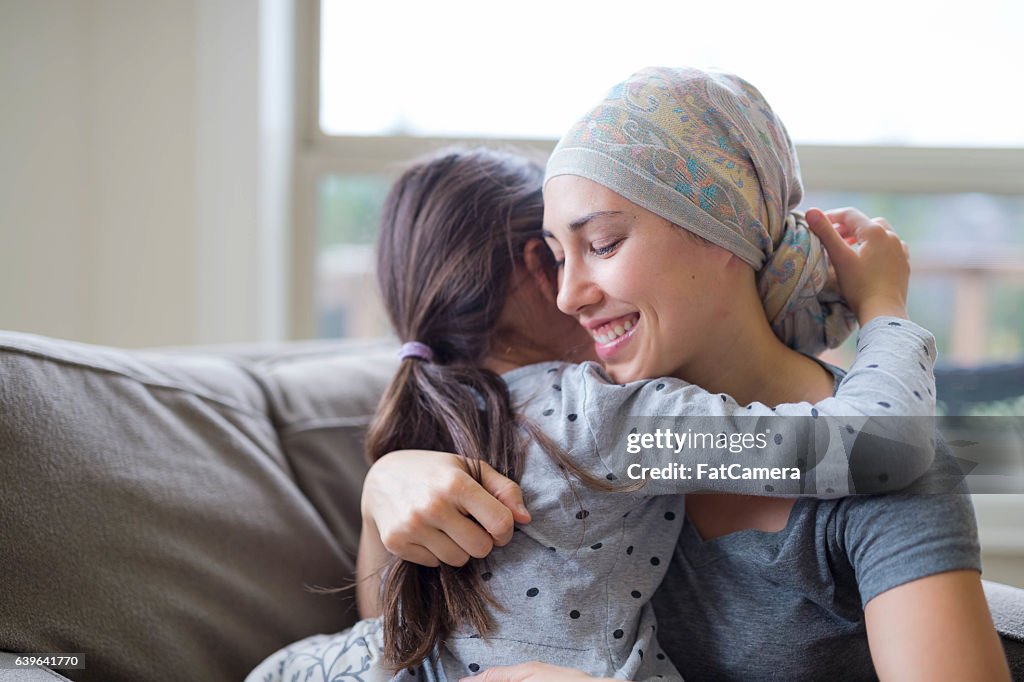 Young adult female with cancer hugging her daughter