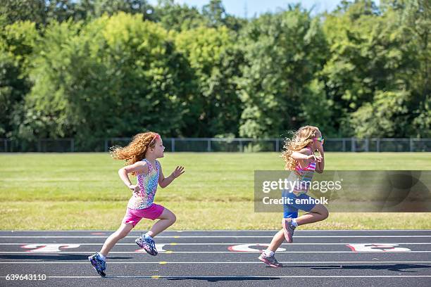 two young girls running on outdoor track - girl side view stockfoto's en -beelden
