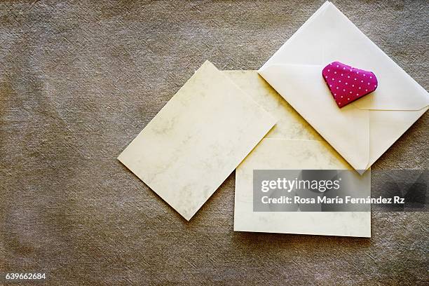 blank gretting card, enveloppe and red paper folded origami handmade heart. flat lay composition, overhead and copy space. subject captured againt soft window lighting over fabric and abstract background. - enveloppe stock pictures, royalty-free photos & images