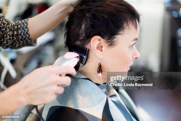 A woman having  her head shaved by a hairdresser