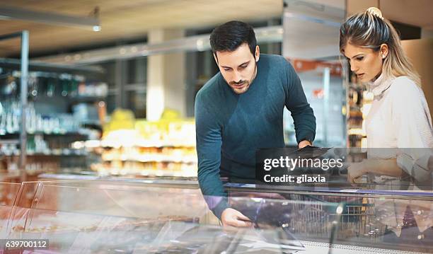 couple shopping in supermarket. - freezer stock pictures, royalty-free photos & images