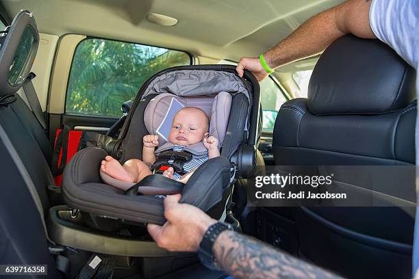 series:infant boy in car seat being put in car - child car seat stock pictures, royalty-free photos & images