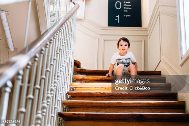 little boy sitting on stairs - escalón y escalera stockfoto's en -beelden