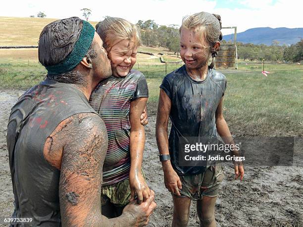 Muddy father kissing daughter during a mud r