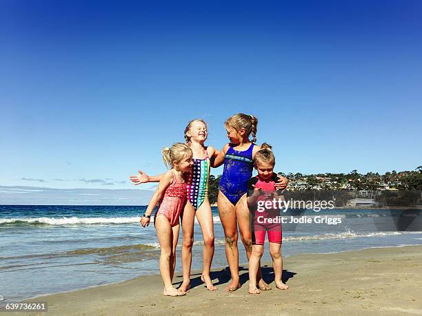 happy children embracing at the beach - physical stance stock pictures, royalty-free photos & images