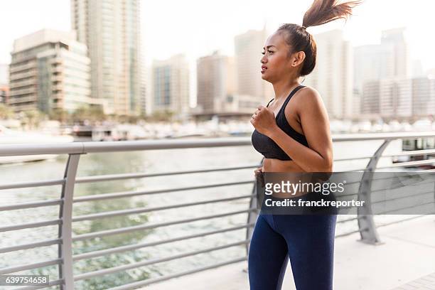 fitness woman running in dubai marina - chubby arab stock pictures, royalty-free photos & images
