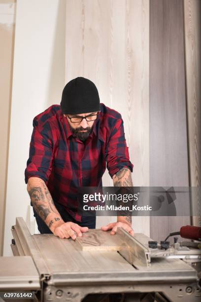adult man with beard and tattoo working in carpenter workshop - table saw stock pictures, royalty-free photos & images
