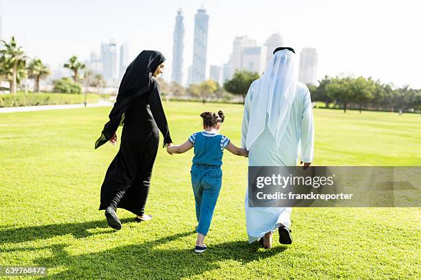 glücksfamilie zu fuß im park in dubai - arab woman walking stock-fotos und bilder
