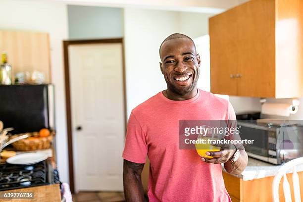 african guy smiling drinking orange juice - juice drink stock pictures, royalty-free photos & images