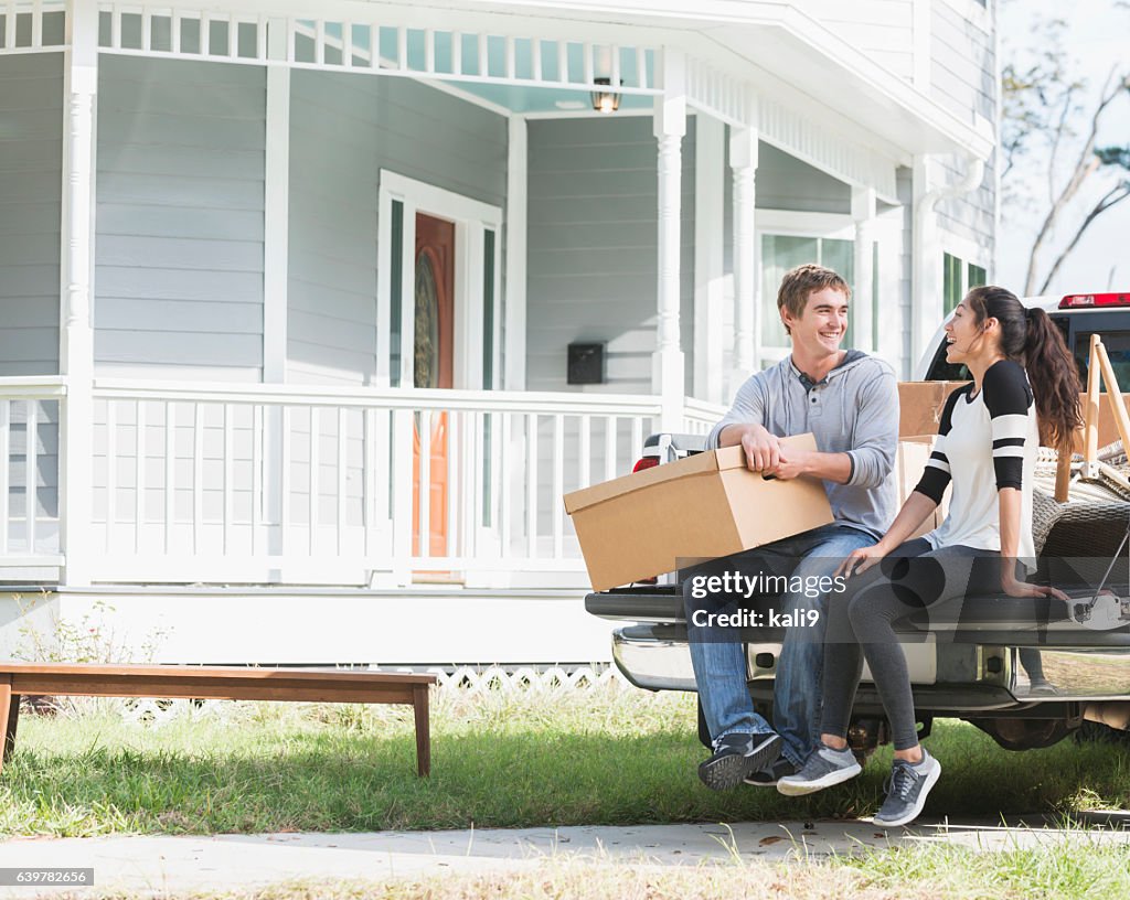 Young couple moving into new home, on pickup truck