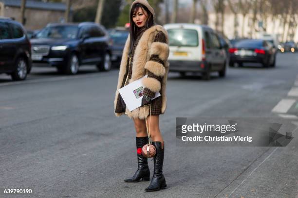 Guest wearing a fur jacket and black boots outside Dior on January 23, 2017 in Paris, Canada.