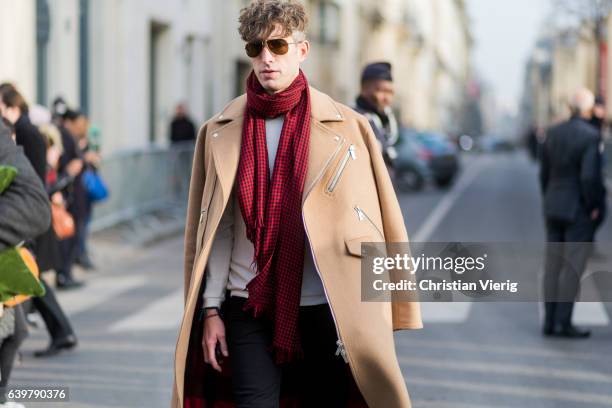 Guest wearing a red checked scarf and beige coat outside Dior on January 23, 2017 in Paris, Canada.