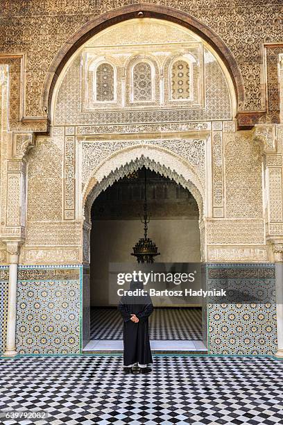 maroccan man walking inside of attarin medersa in fes, morocco - fes morocco stock pictures, royalty-free photos & images