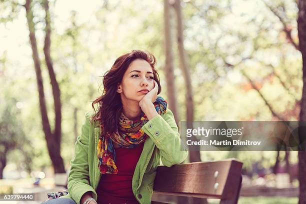 ragazza infelice seduta in panchina - delusione foto e immagini stock