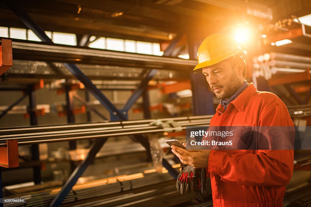 Manual worker text messaging on cell phone in aluminum mill.
