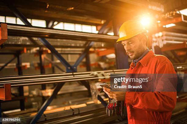 manual worker text messaging on cell phone in aluminum mill. - metallic look stock pictures, royalty-free photos & images