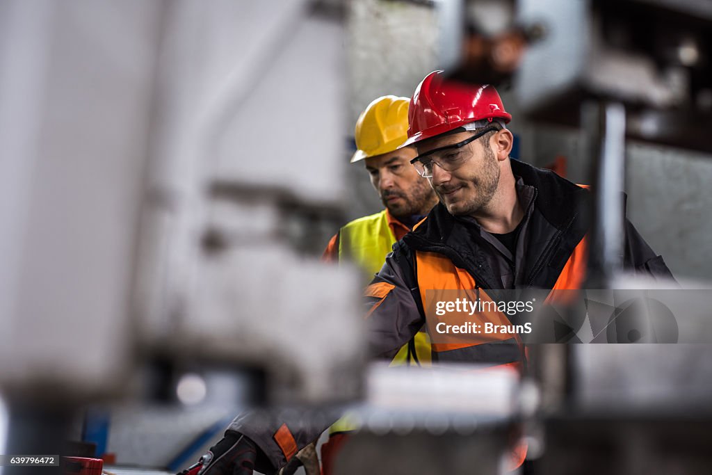 Metal workers cooperating while working in aluminum mill.