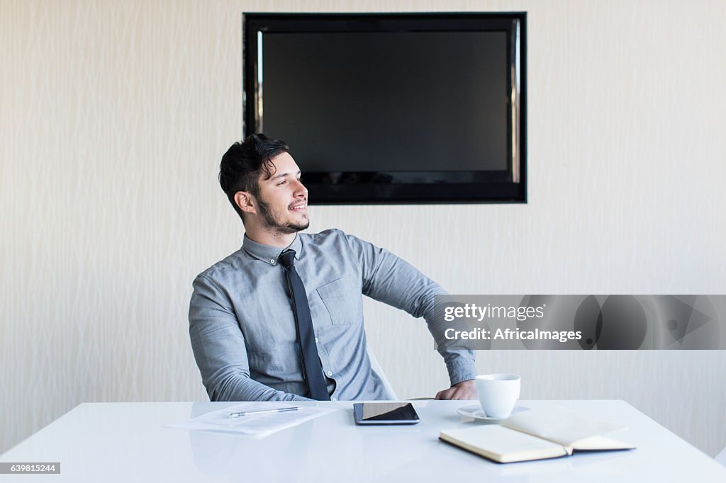 Businessman sitting at his desk smiling.