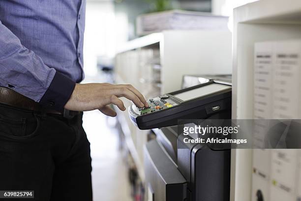 businessman pressing the start button to print. - photocopier stock pictures, royalty-free photos & images