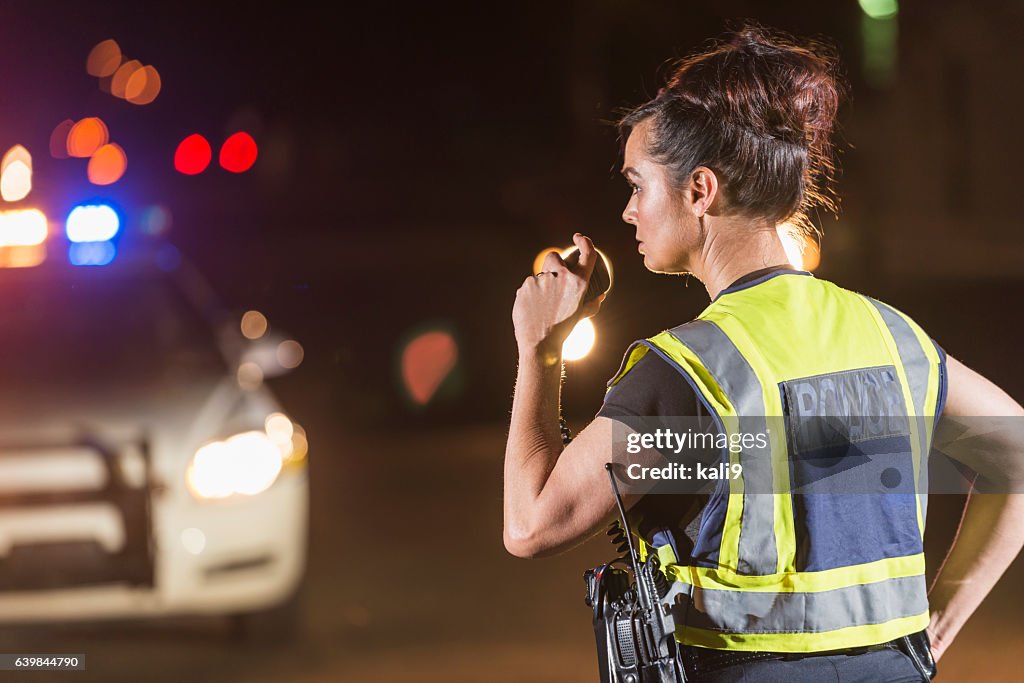 Mujer policía por la noche, hablando en radio