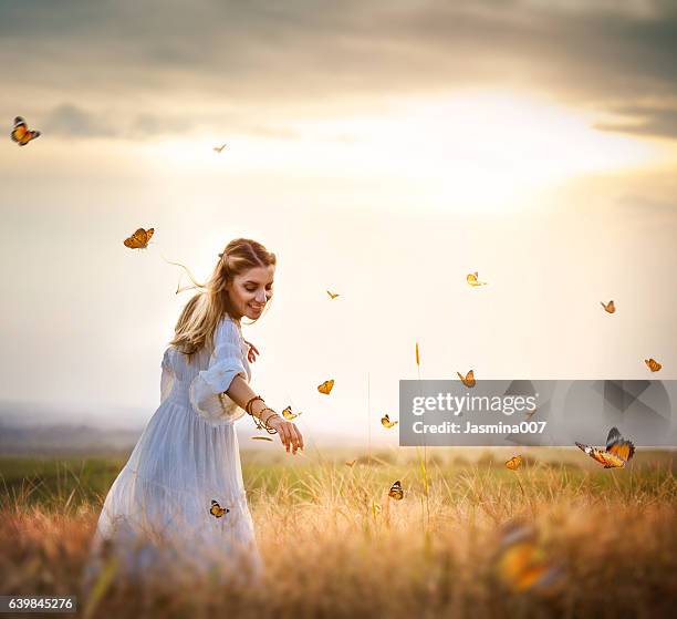 girl in meadow with flitting butterflies - schubvleugelige stockfoto's en -beelden