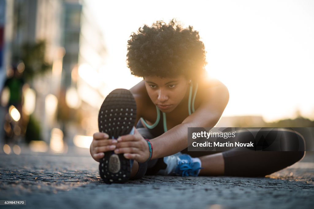 Teenager exercises in city at sunset