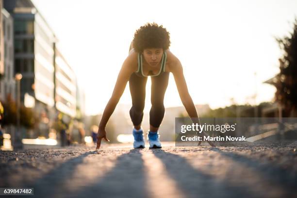mixed race athletic girl all set to run down the street - startstreep stockfoto's en -beelden