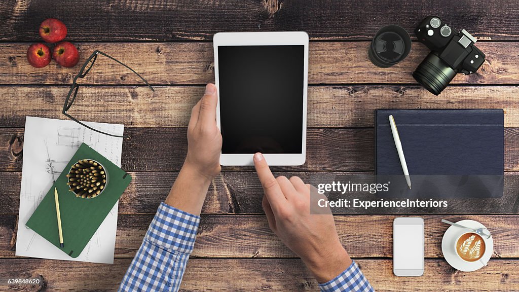 Man hipster holding tablet knolling overhead view