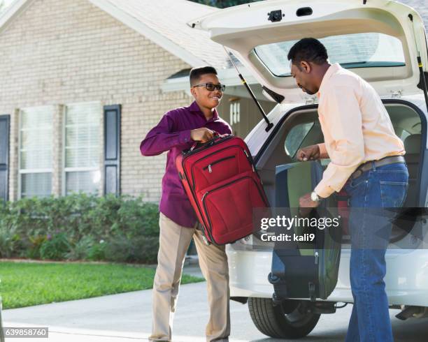 father and son loading suitcases into car - load lifter stock pictures, royalty-free photos & images