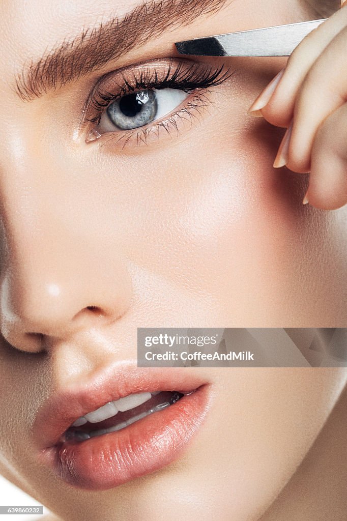 Beautiful girl plucks eyebrows
