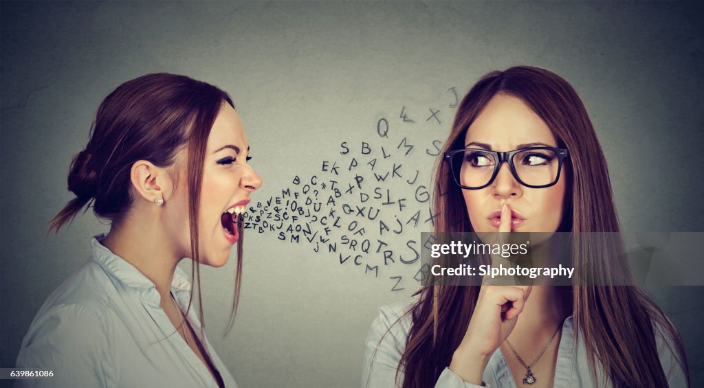 Angry woman screaming at herself with finger on lips gesture