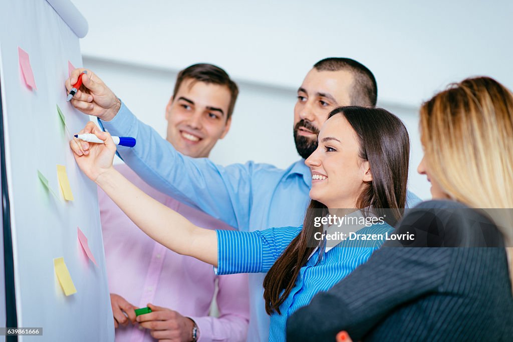 Group of people writing on flip-chart in office