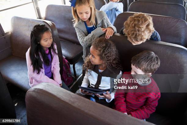 enfants assis à l'intérieur de bus scolaire avec tablette numérique - school bus stock photos et images de collection