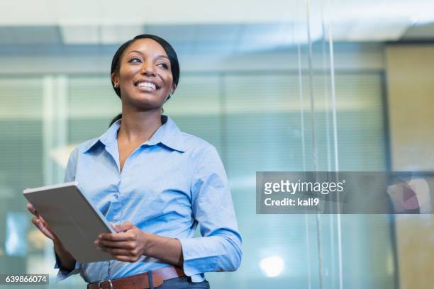 african american woman in office holding digital tablet - minority groups professional stock pictures, royalty-free photos & images