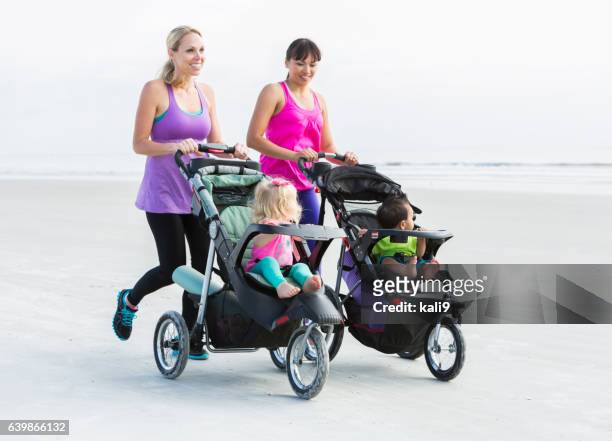 two mothers and babies in strollers jogging on beach - jogging stroller stockfoto's en -beelden