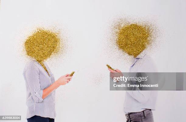 man and a woman texting with golden heads - obscured face phone stock pictures, royalty-free photos & images