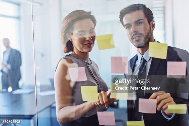 teamwork macht das geschäft erfolgreich - team looking at adhesive notes in board room during meeting stock-fotos und bilder