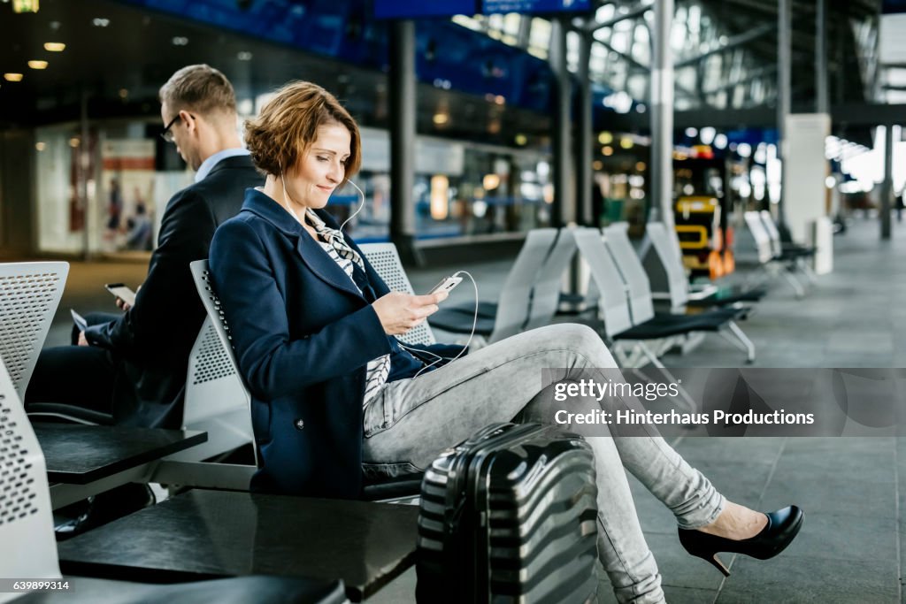 Mature businesswoman waiting at the airport while using a smart phone