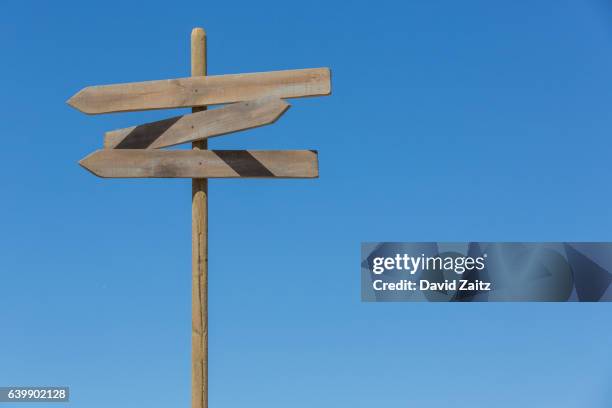 directional signpost against sky - wooden sign stock-fotos und bilder