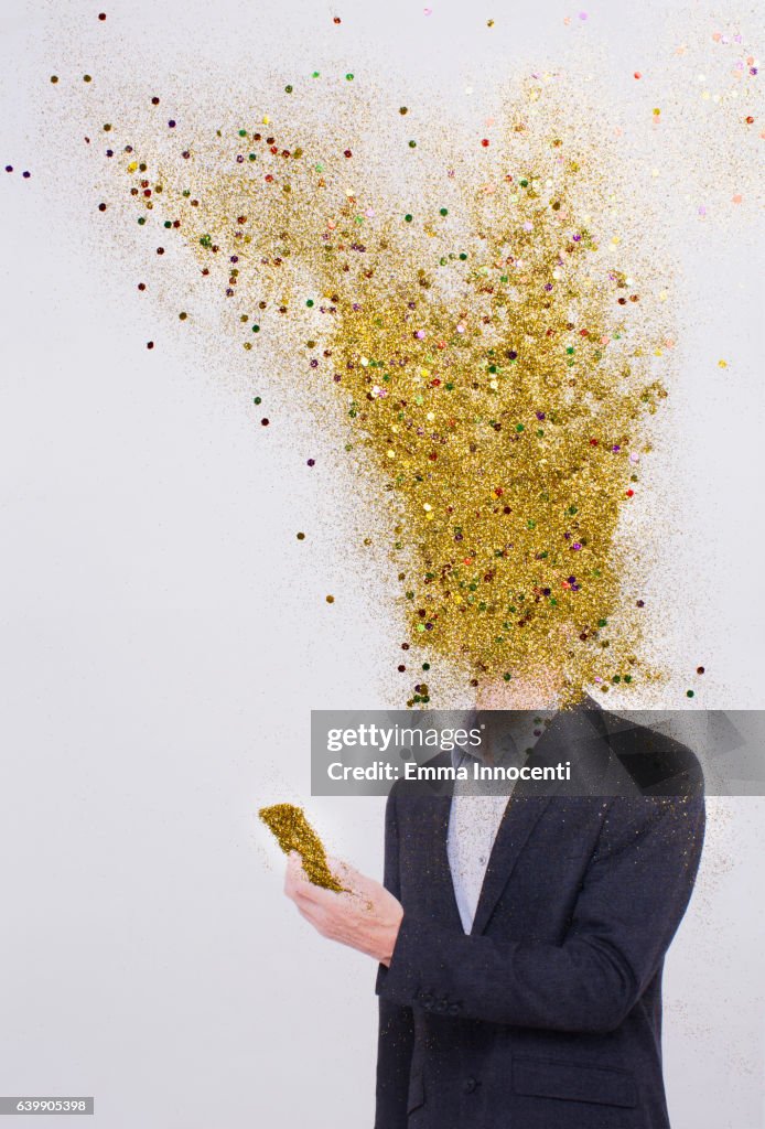 Business man head exploding into gold dust