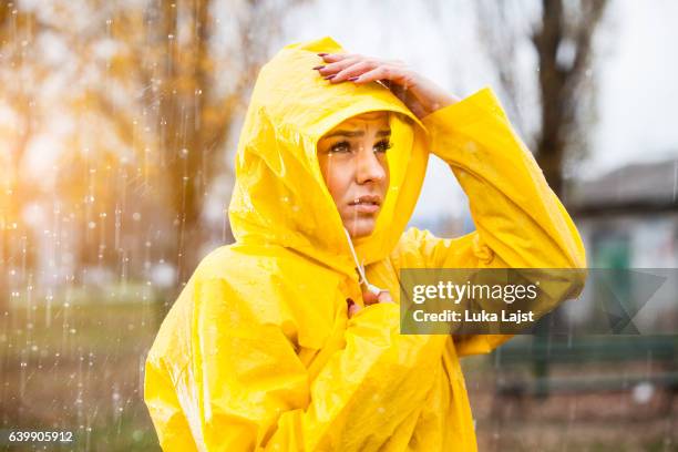 young woman in yellow raincoat on the rain - rain coat stock pictures, royalty-free photos & images