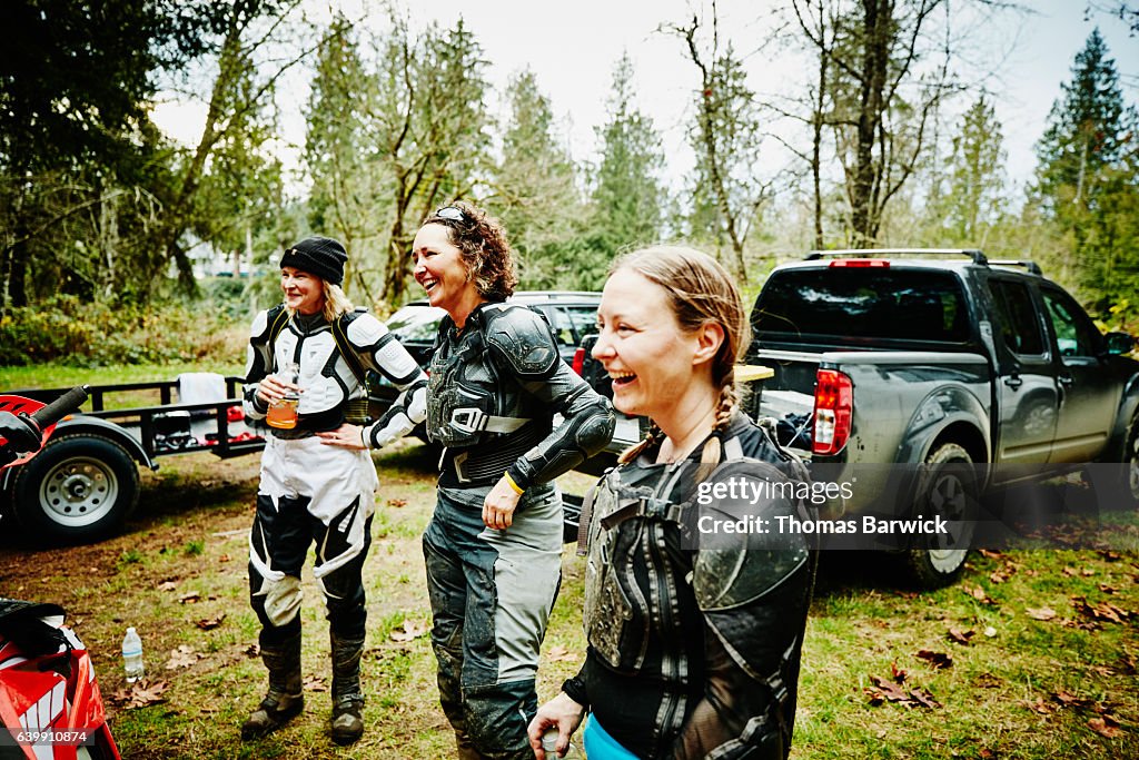 Laughing female motorcyclists hanging out together after riding dirt bikes