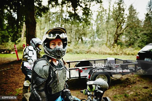 female motorcyclist smiling after riding dirt bikes with friends - dirty car stock-fotos und bilder