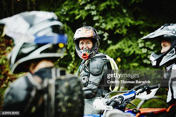 female motorcyclists with muddy face laughing with friends while riding dirt bikes - motocross stock photos et images de collection