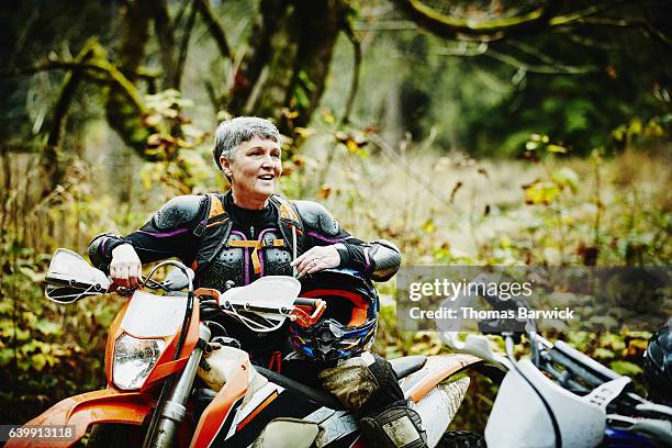 female motorcyclist in discussion with friends after riding dirt bikes - woman motorcycle stock pictures, royalty-free photos & images