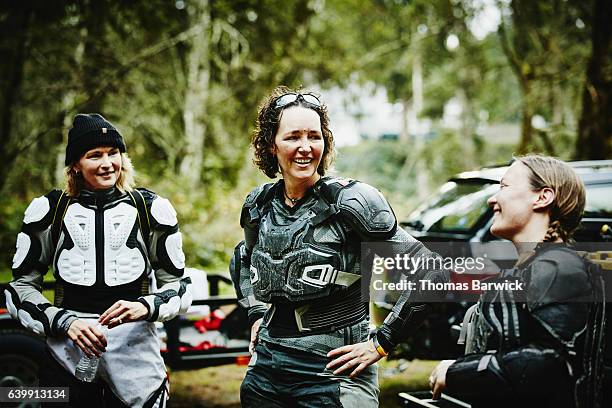 laughing female motorcyclists hanging out after riding dirt bikes - motorradfahrer stock-fotos und bilder